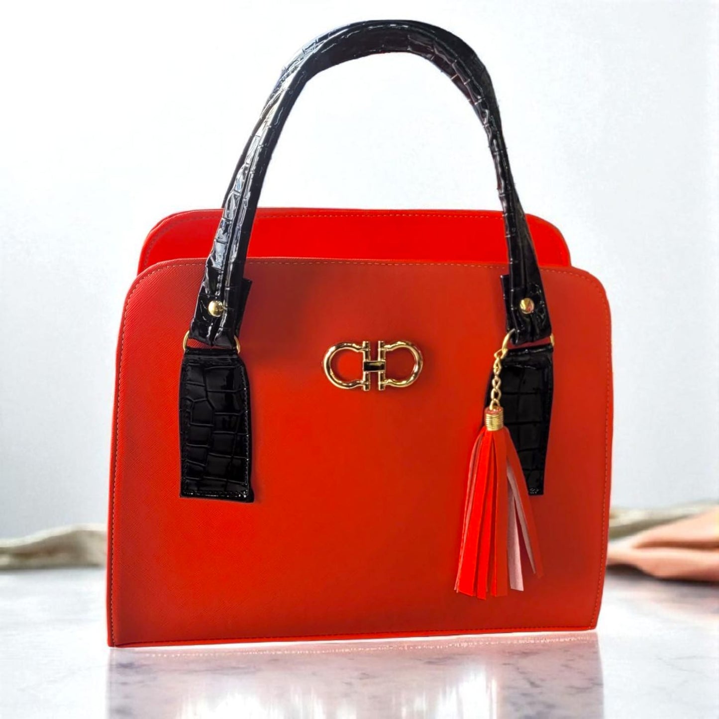 "Bolsa de Mano Roja con Asa Negra y Colgante de Flecos – Elegante y Moderna"