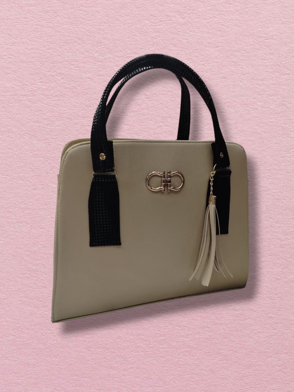 Bolso beige con asas negras y borla colgante estilo minimalista
